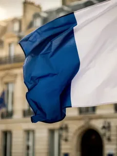 French flag waving in front of the Ministry of Finance building in Paris, representing the 2026 budget announcement.